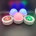 Colourful gradient 3D shooting light night light with remote control on a surface.