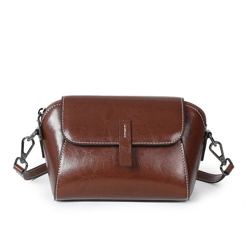 Brown leather women's crossbody messenger bag showing shell shape and visible stitching.