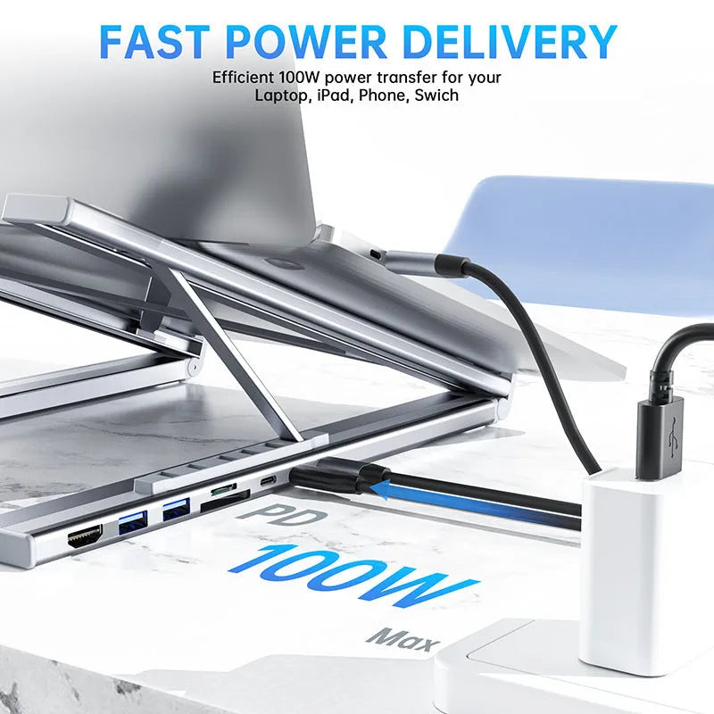 Aluminium folding laptop stand with built-in multi-port docking hub on a desk.