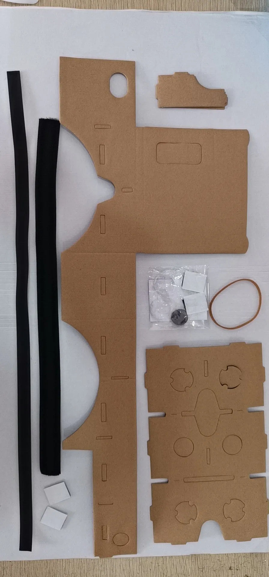 Pink and white cardboard VR glasses for smartphones with 3D lenses and a rubber strap.