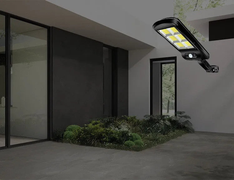 Black outdoor solar-powered security light with motion sensor on a wall.