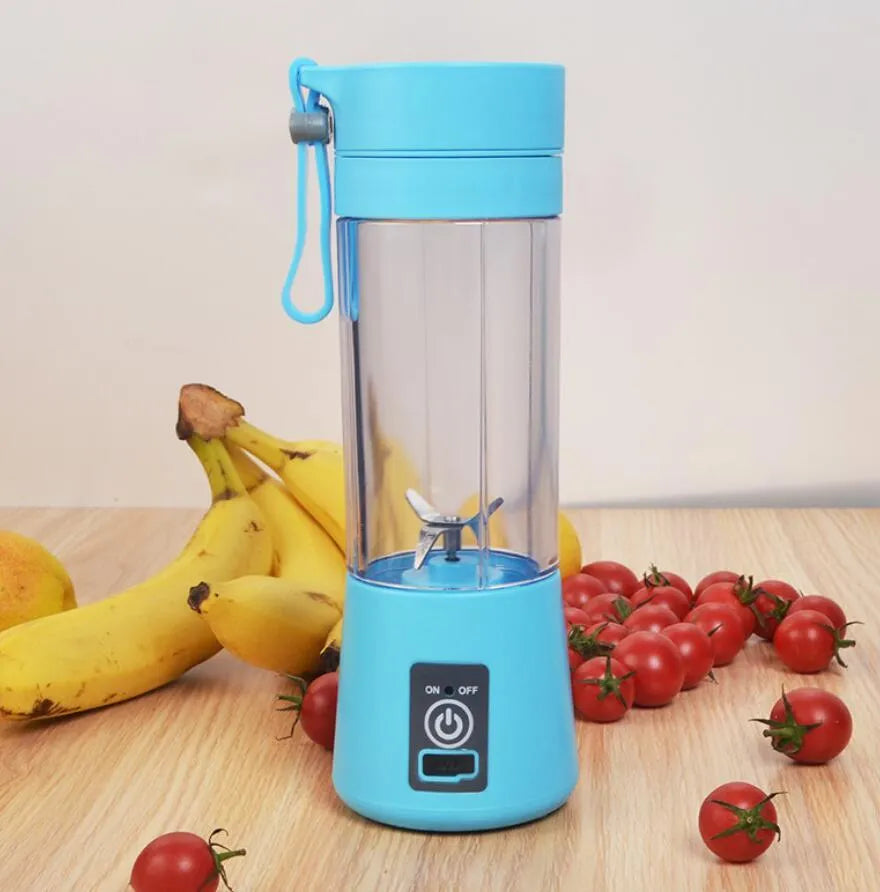 Pink mini USB electric centrifugal fruit juicer with stainless steel blade on a table.