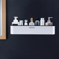 Black adhesive plastic bathroom shelf mounted on a wall holding shampoo and shower gel bottles.