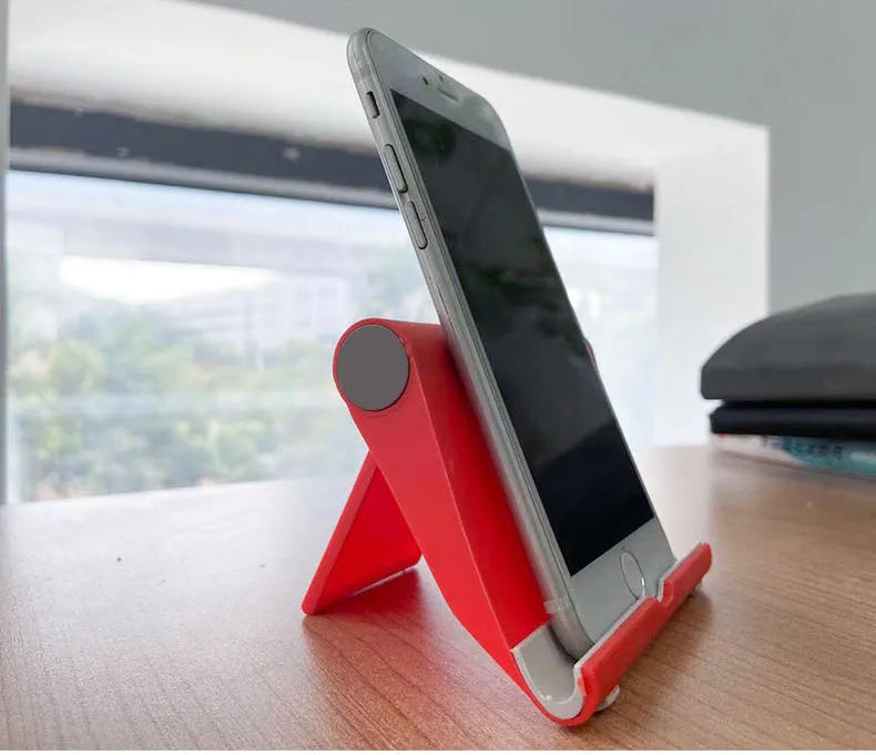 Black PE folding mobile phone stand holding a tablet at an angle on a desk