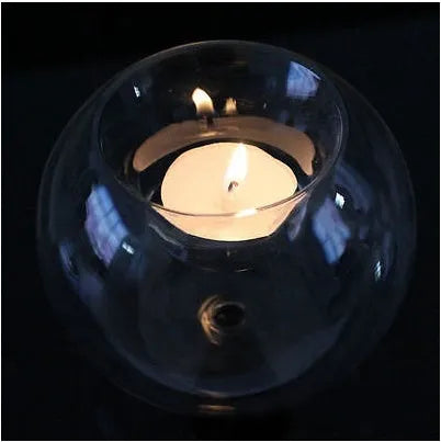 Clear round handmade hollow glass candle holder sphere on a table.