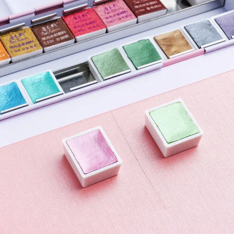 Pearl-effect solid watercolour paint pans in a set showing iridescent colours.