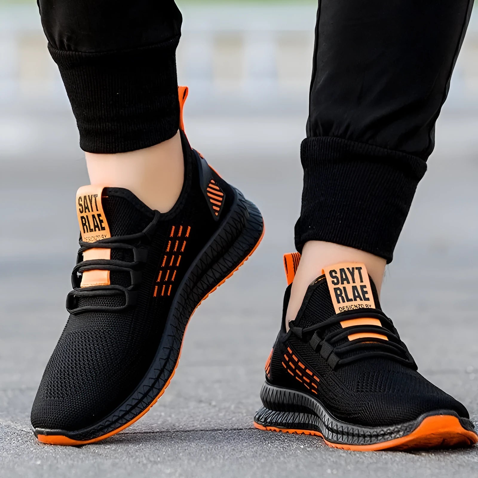 Men's black casual sneakers with flying weave upper, cross straps, and a low flat profile on a white background.