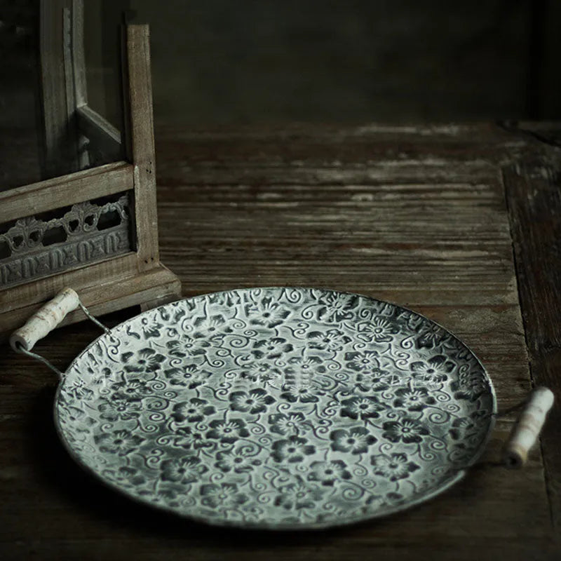 Black round wrought iron belt storage tray shown in two sizes on a wooden surface.