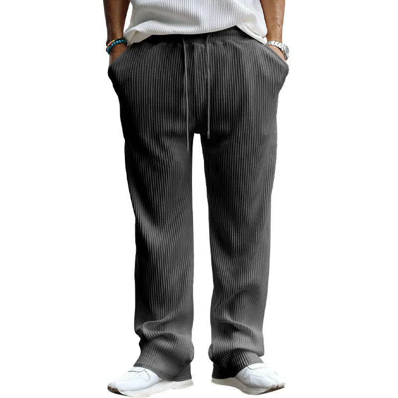 Man wearing loose high-waisted straight-leg casual trousers in a striped pattern.
