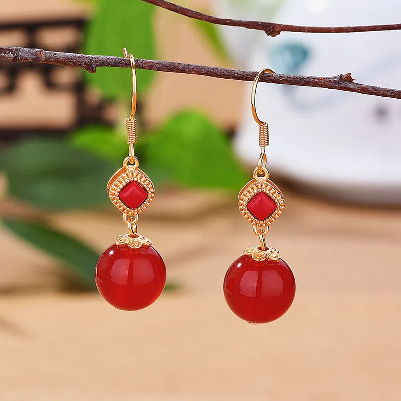 Geometric drop earrings with red agate round beads and sterling silver inlaid jasper stones on a copper base.
