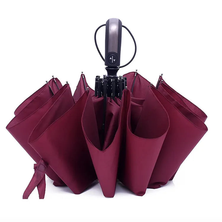 A folded black automatic business umbrella with a rubber handle, showing its triple folding design.