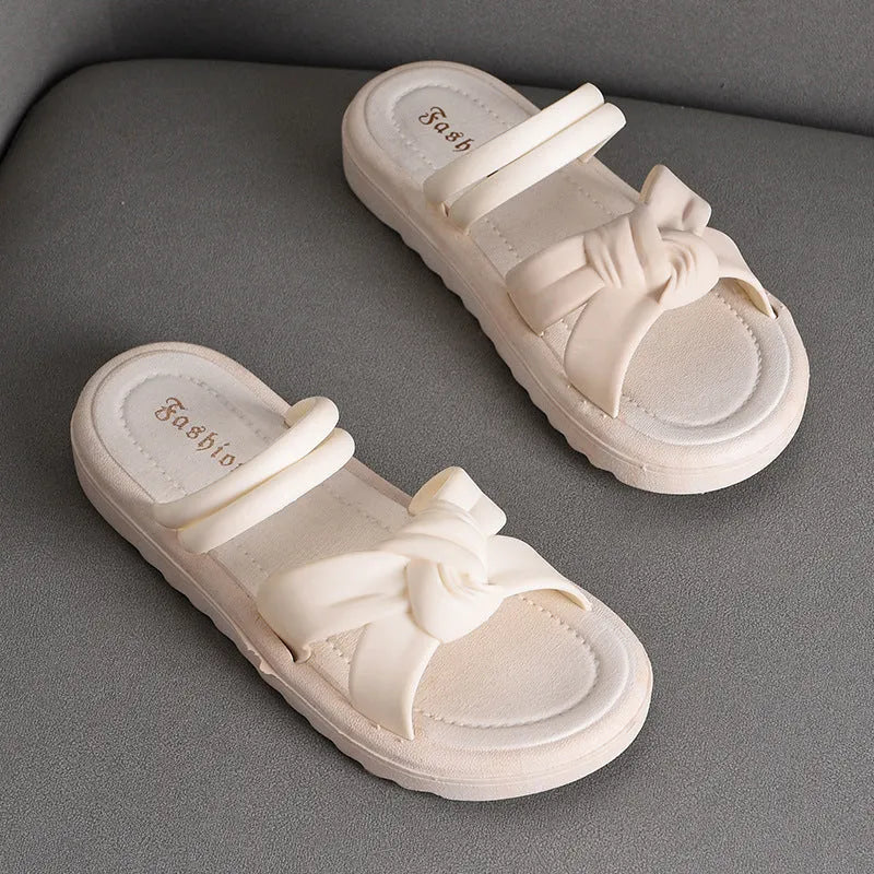 Women's black PVC sandals with soft back, floral detail, and a thick height-increasing sole.