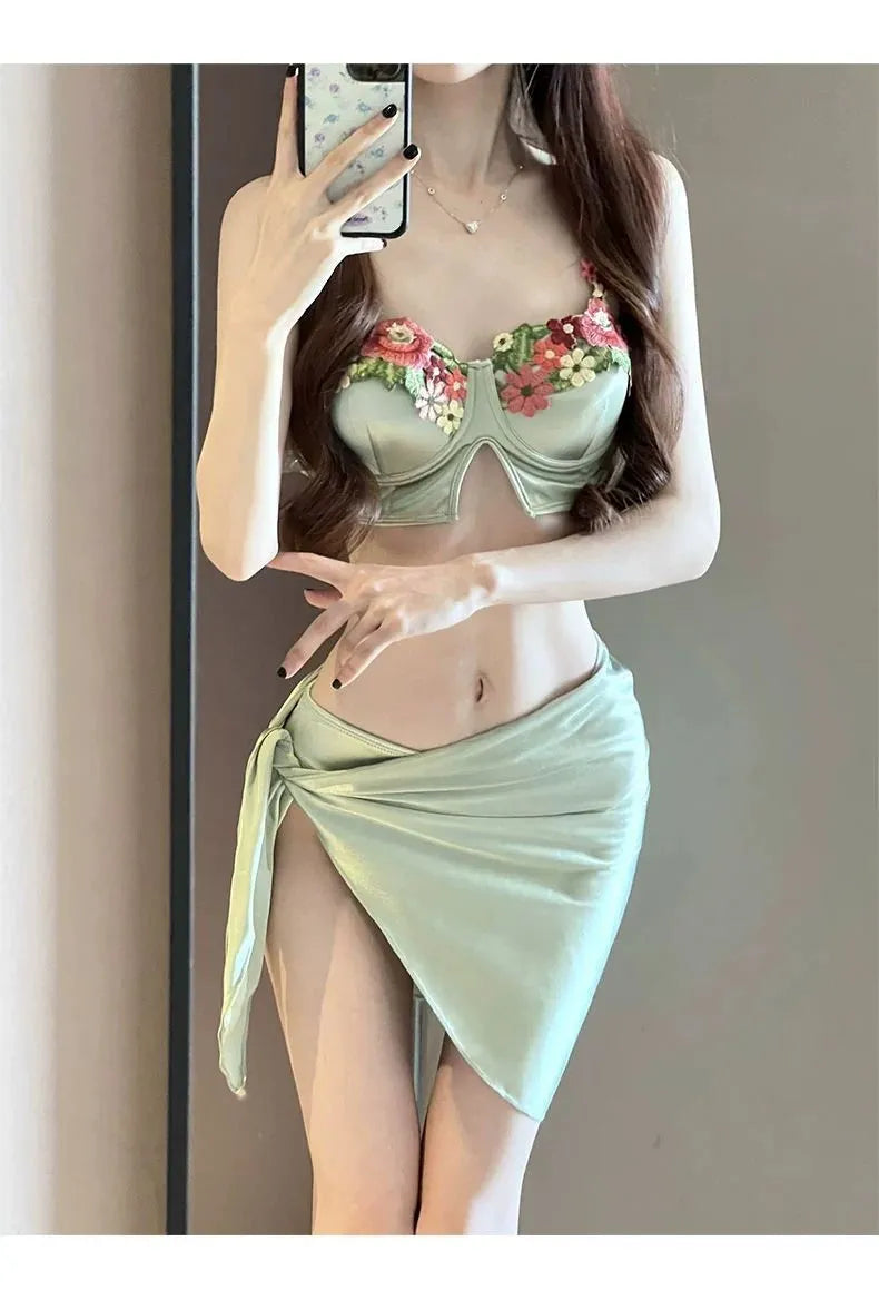 Green three-piece women's bikini swimsuit with triangle top, briefs, and skirt
