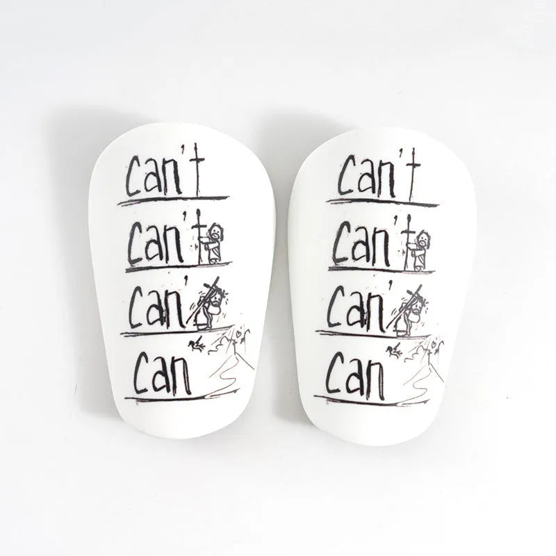 A pair of white and black PU football shin guards for S and XS sizes.