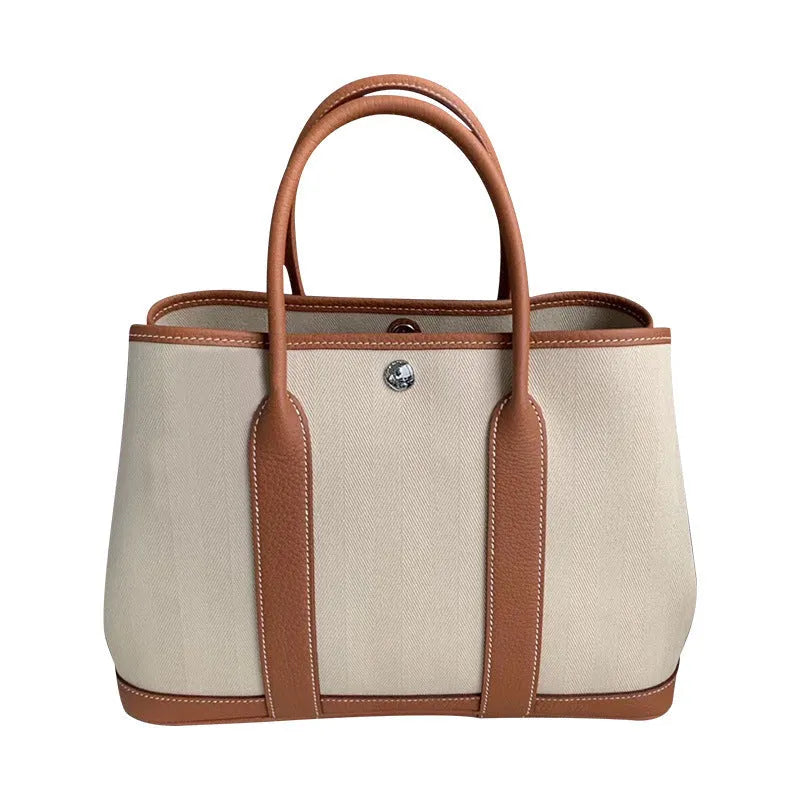 Women's canvas bucket tote bag with genuine leather trim, shown with crossbody strap and carry handle
