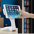 White aluminium tablet stand with adjustable clamp holding a tablet