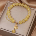 Women's natural citrine bracelet with a gold-tone Chinese character charm and tassel on an adjustable chain.