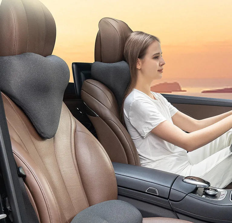 Dark grey memory foam car neck pillow on a car headrest.