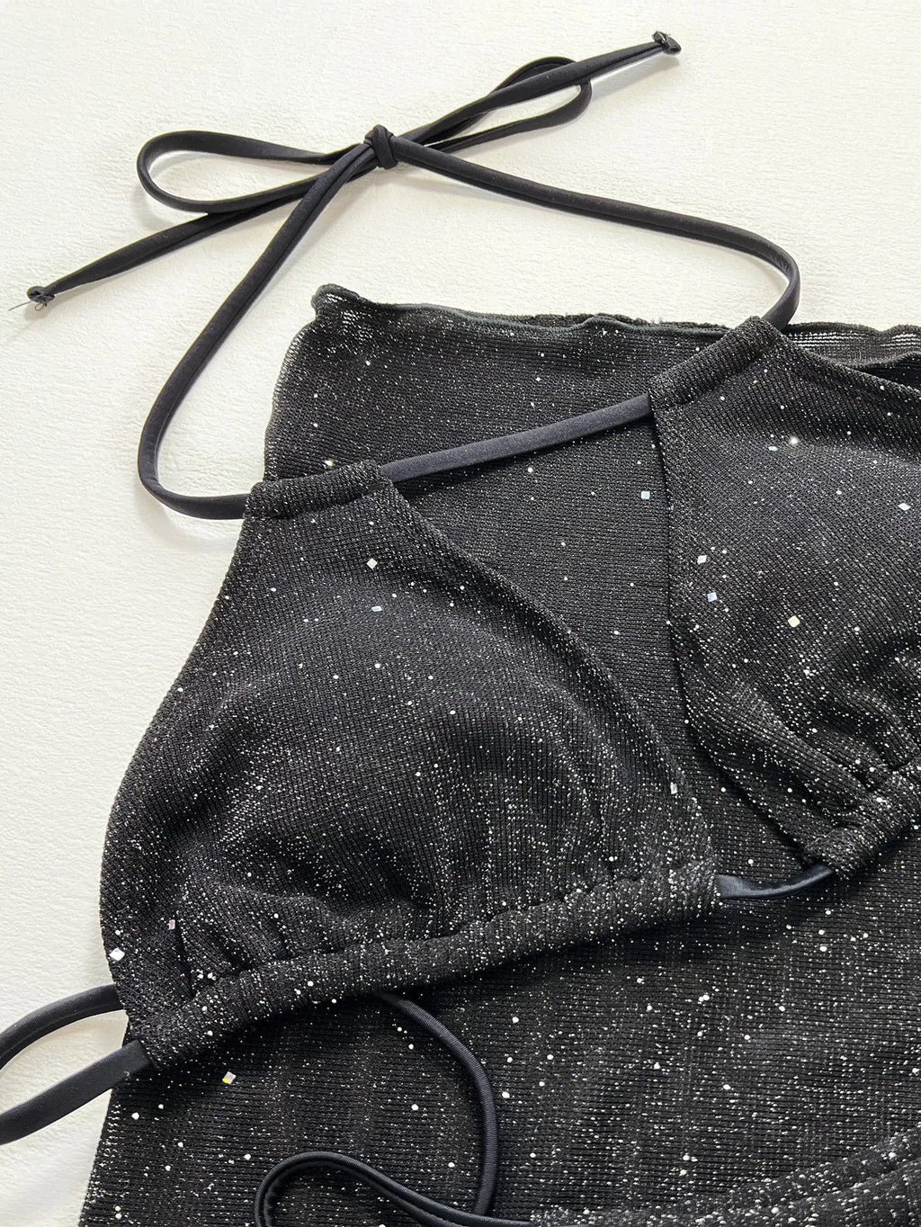 Black three-piece bikini set with triangle top and high-waisted shorts on swimwear model