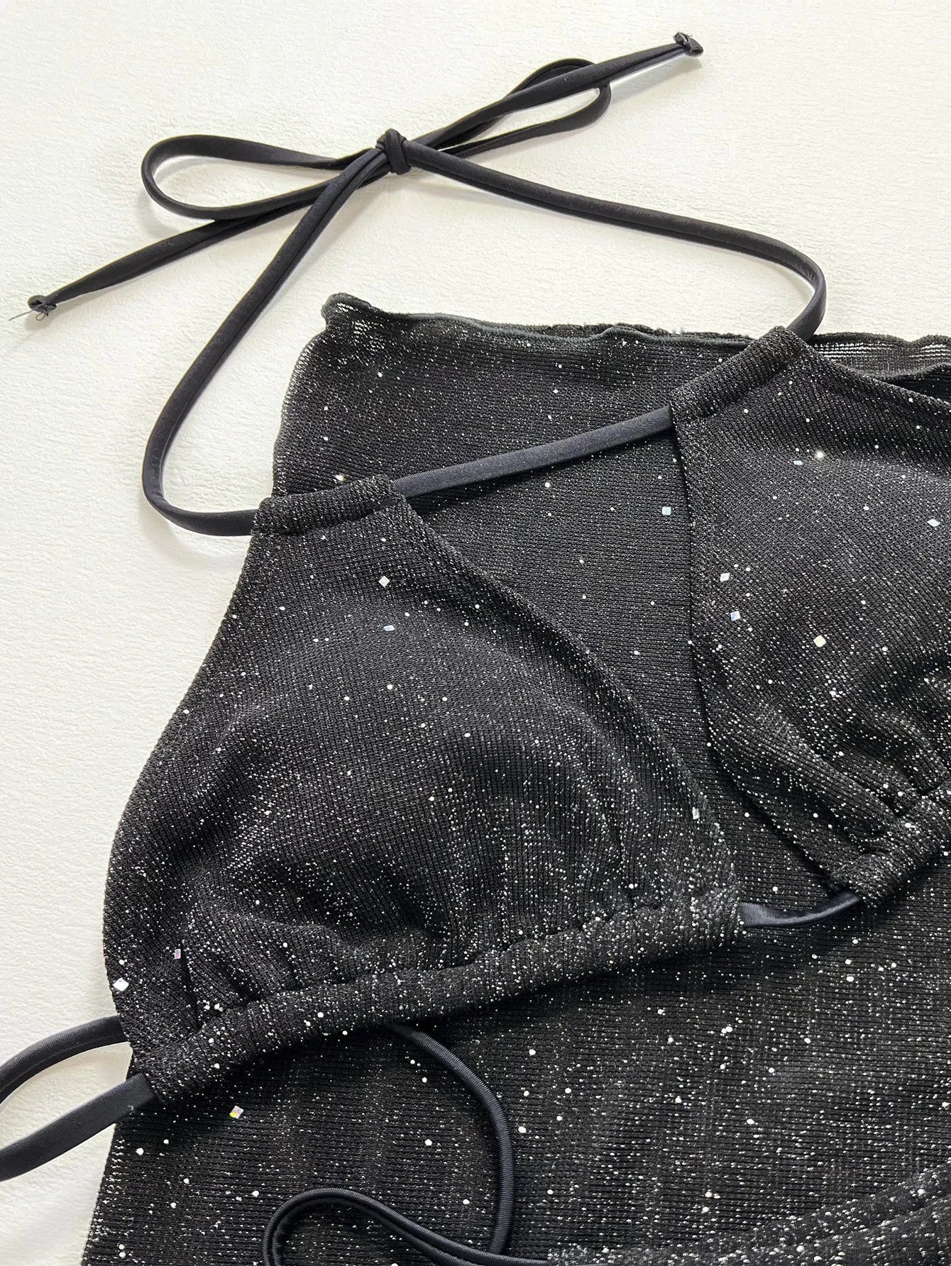 Black three-piece bikini set with triangle top and high-waisted shorts on swimwear model