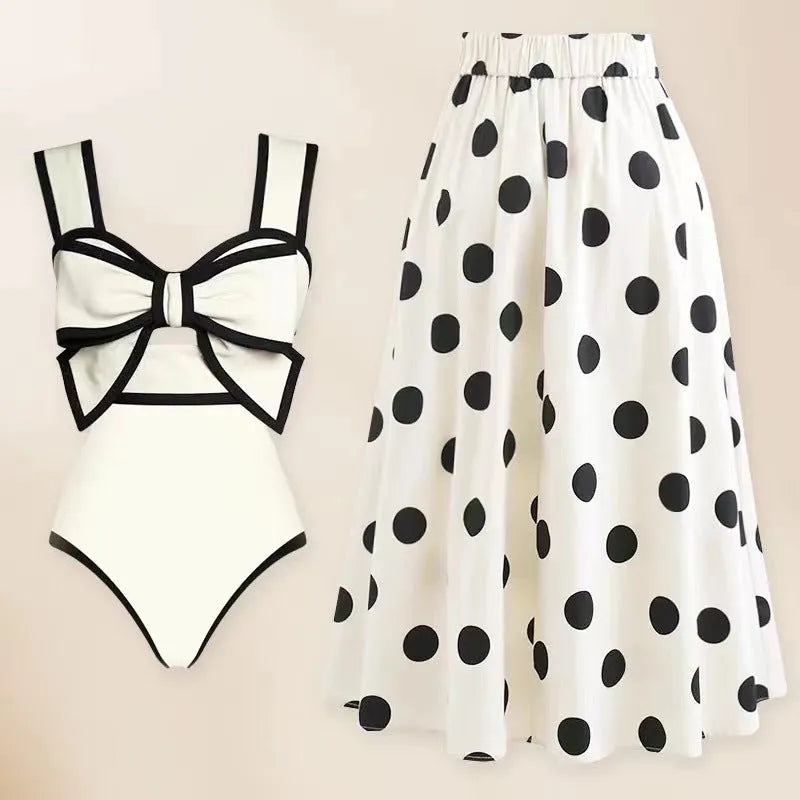 Women's black one-piece swimsuit with white skirt and bow detail on front.