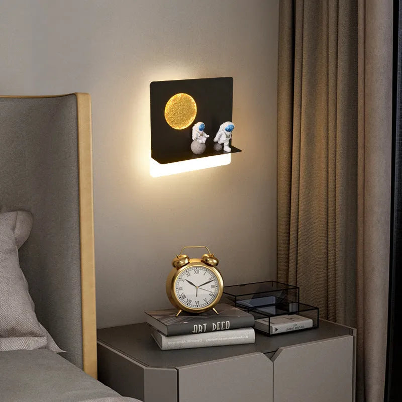 White astronaut-shaped wall lamp with a small shelf, mounted on a bedroom wall.