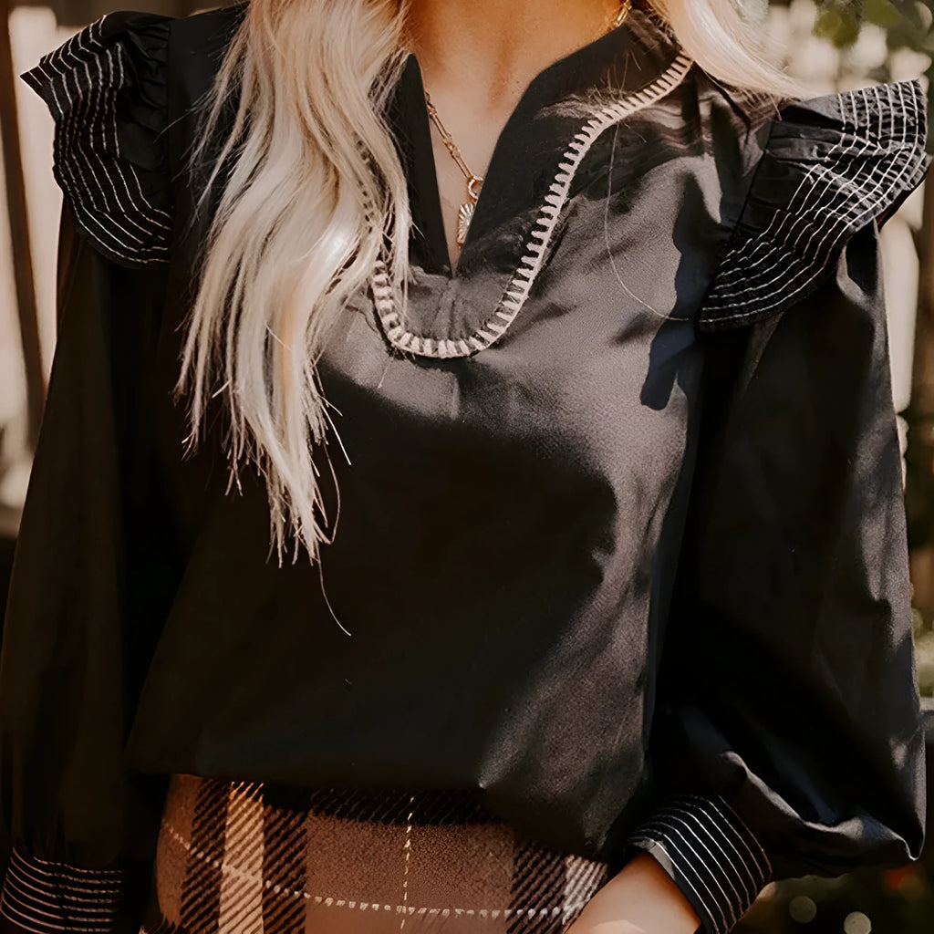 Black V-neck long sleeve blouse with a decorative ruffle and contrast stitching.