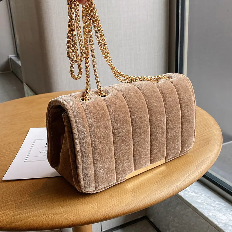 One shoulder velvet chain crossbody bag in solid colour, small square shape with gold chain strap, on white background.