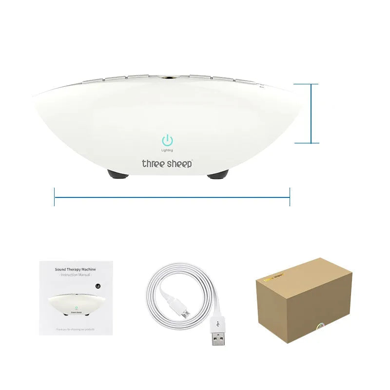 White-coloured white noise sleep aid machine with mechanical control buttons on a bedside table.