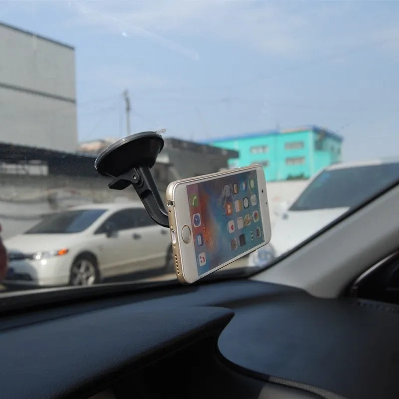 Black magnetic car phone holder mounted on a dashboard, showing a smartphone attached at an angle.