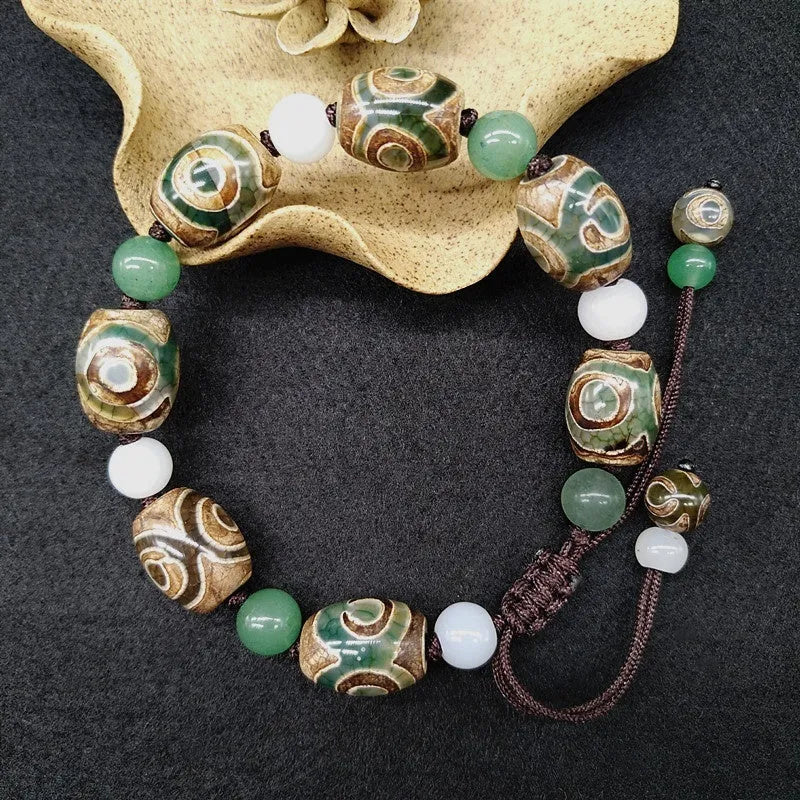 Green agate hand-woven Tibetan bracelet with three-eye geometric design on a wrist.