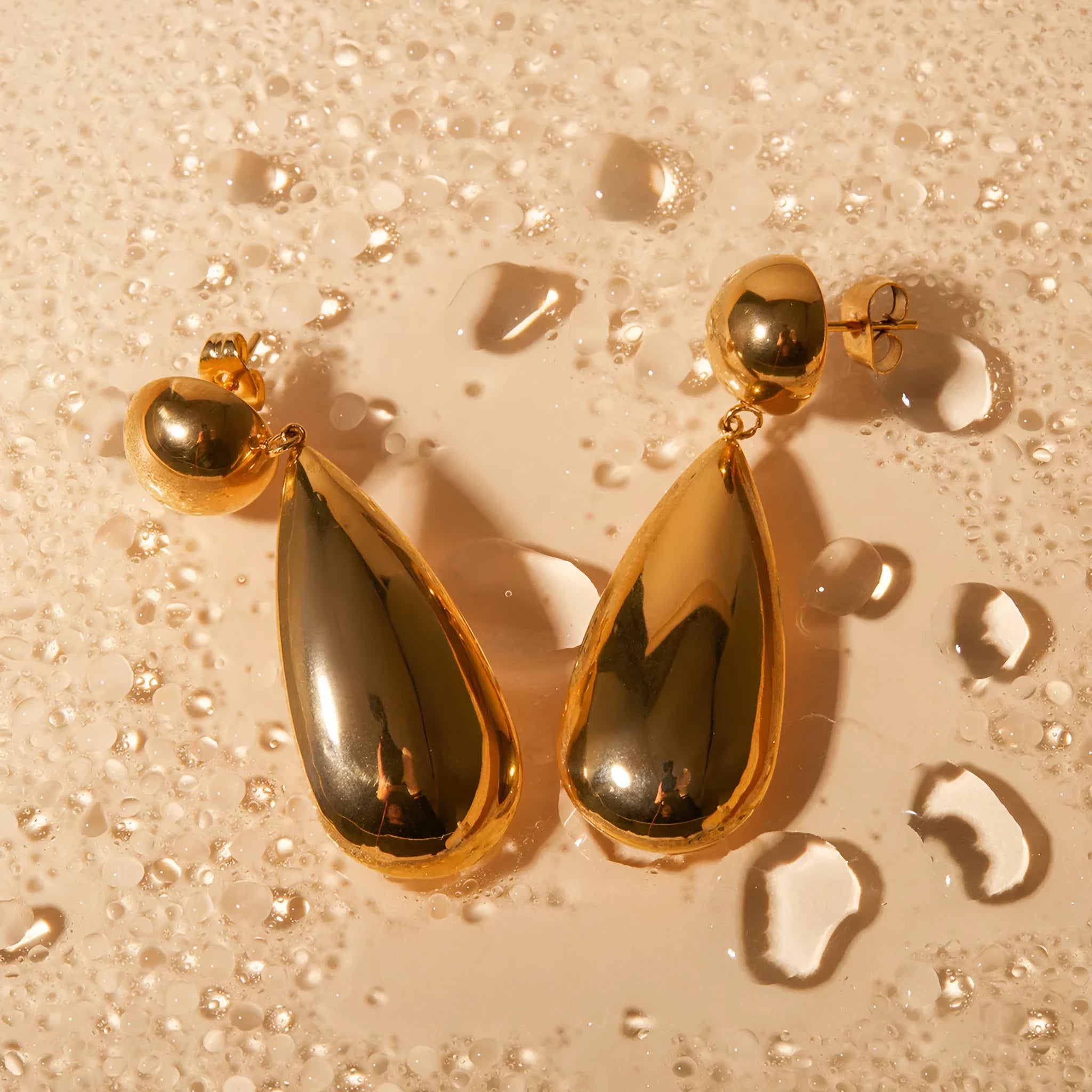 Gold stainless steel water drop shaped hemisphere pendant earrings for women.