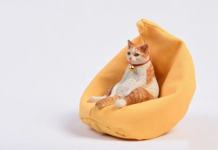 Small 7.5cm high cat model car ornament with fabric sofa on a dashboard.