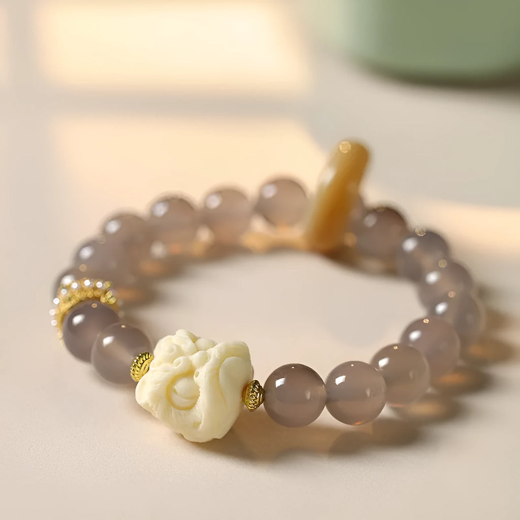 Hand-woven bracelet with large round grey agate and mellite beads on wrist.