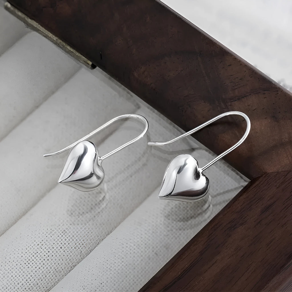 Silver-coloured three-dimensional heart-shaped earrings with glossy finish on copper