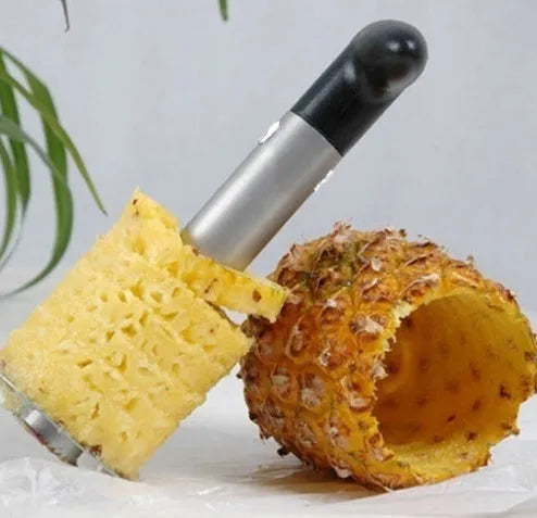 Stainless steel pineapple corer slicer with coloured plastic handle on a kitchen worktop.