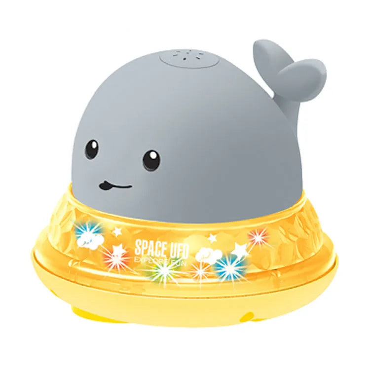 White and blue electric whale bath toy spraying water with flashing lights on a bathroom surface.