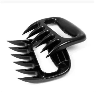 Two black bear claw-shaped meat shredding forks with patterned handles on a kitchen surface.