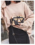 Women's hard black flap handbag with single strap, rivet details, and hasp closure.