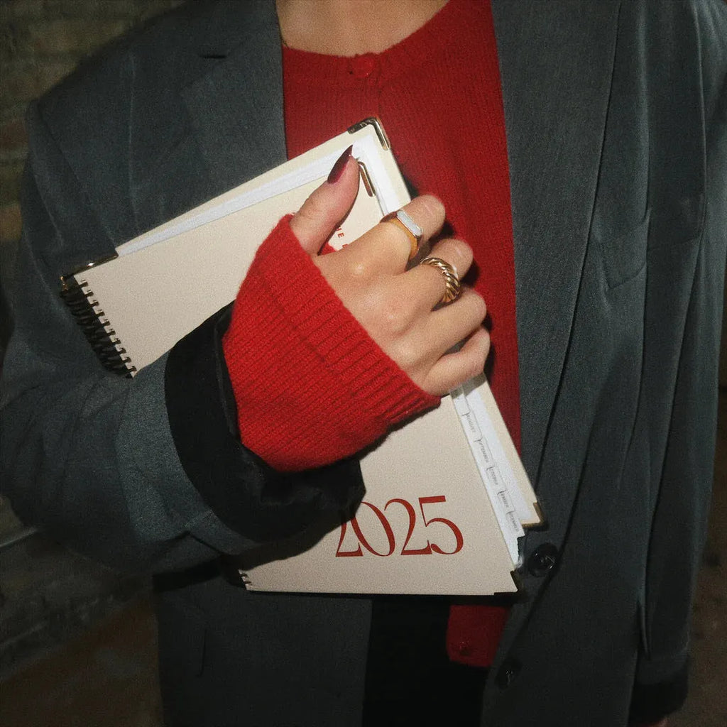 Cherry red daily schedule coil notebook open showing wire binding and printed schedule pages
