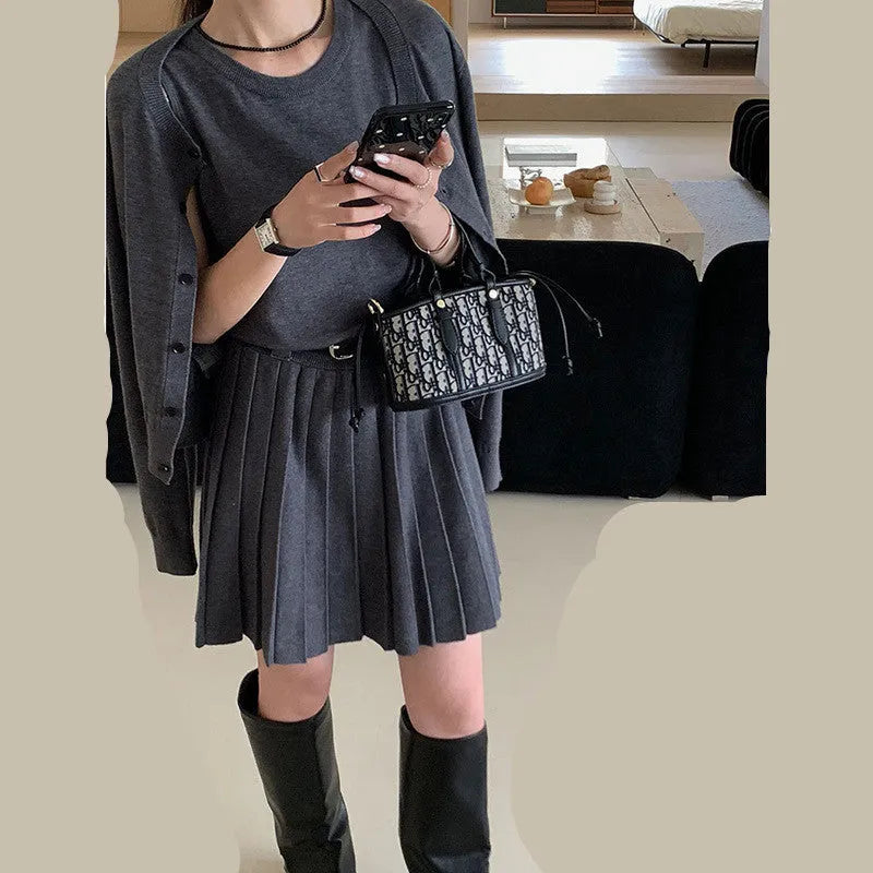 Women's grey art retro knitted vest skirt and long sleeve cardigan two-piece set on a hanger.