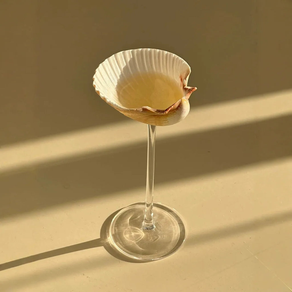 Handmade glass water cup with creative conch shell design, clear glass finish, side view