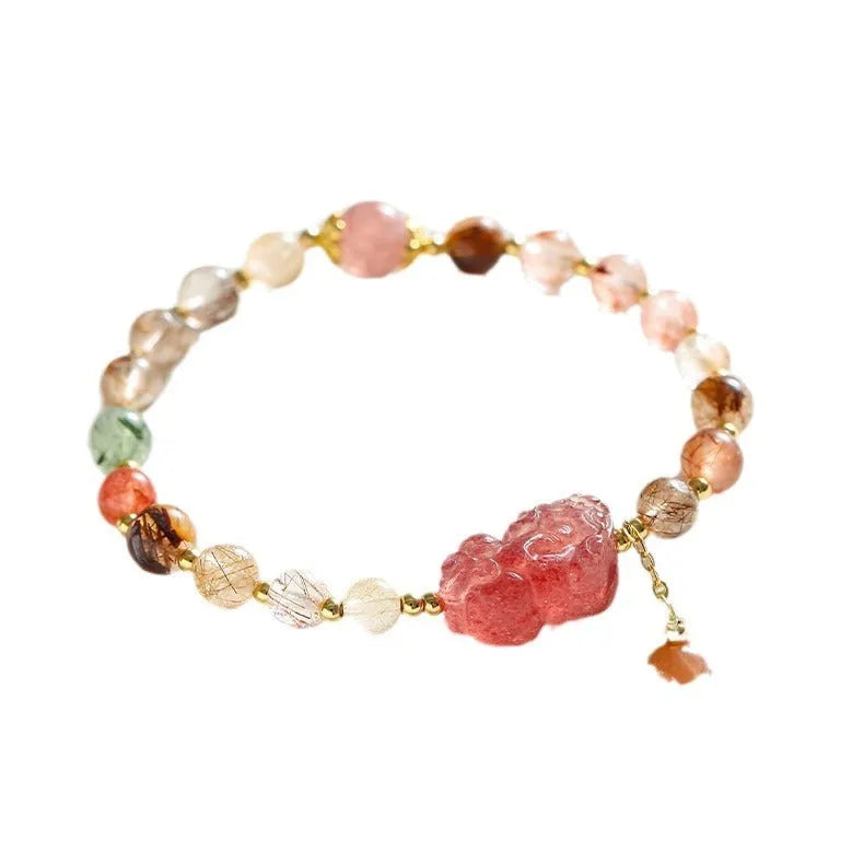 Copper women's bracelet with a pink Strawberry Quartz crystal and a gold-toned Pixiu charm, alongside smaller crystal beads.