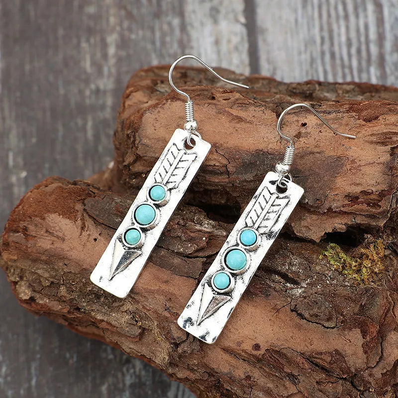 Long silver geometric drop earrings with blue turquoise stone inlays on a retro-style setting.