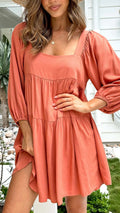 Orange backless children's dress with square collar and puff sleeves on a hanger.