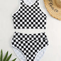 Backless one-piece women's swimsuit with black and white chessboard plaid pattern and white suspender straps.