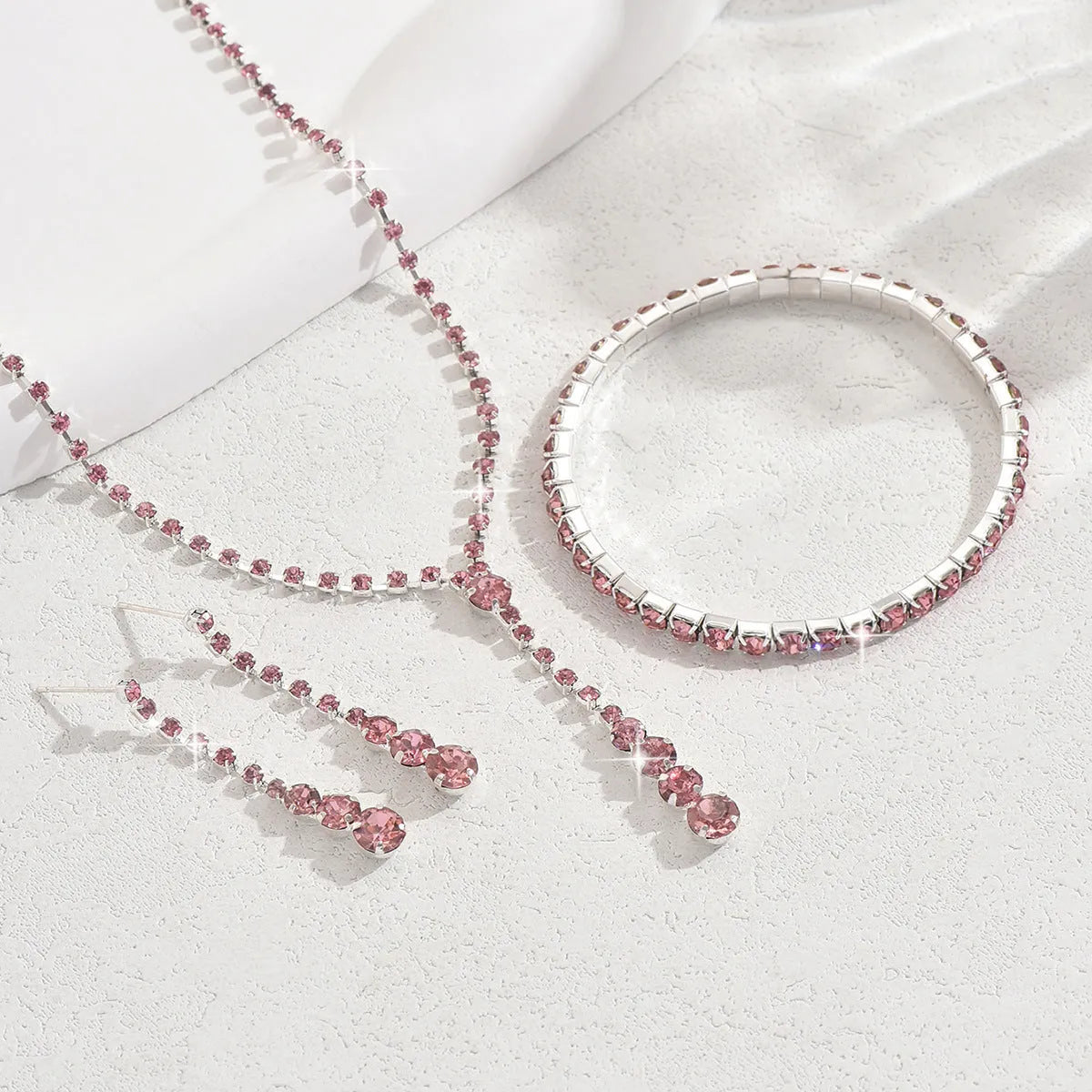 Women's rhinestone jewellery set with elastic bracelet, snake bone chain necklace, and earrings in rose gold finish.