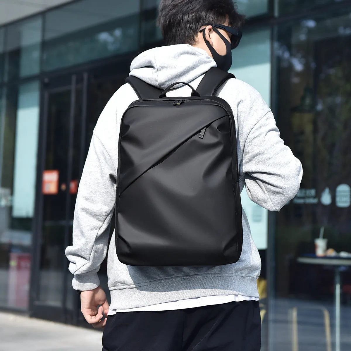 Large black waterproof PU leather computer backpack with simple design and sewing thread detailing