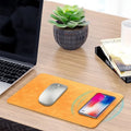 Brown leather wireless charging mouse pad with Micro USB cable on a wooden desk.