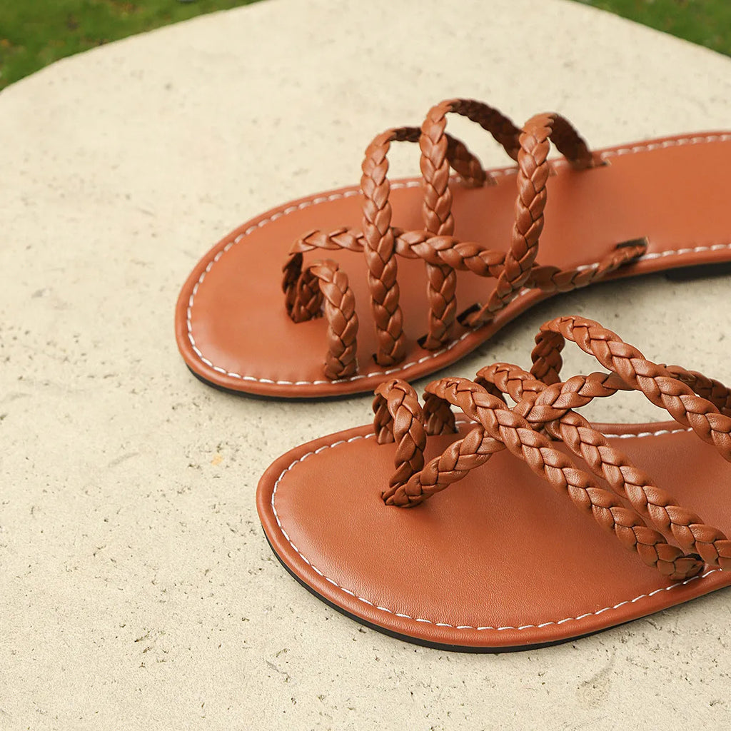 Women's white woven clip-toe flat sandals with a rubber sole on a plain background.
